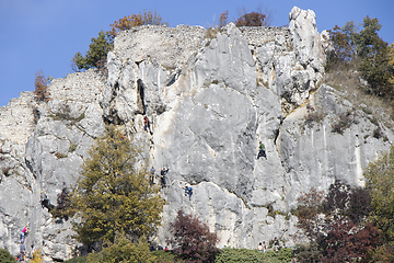 Image showing Group of young people climbing natural high rocky wall