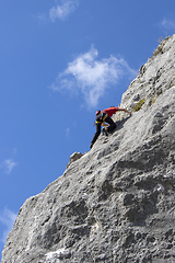 Image showing Young sports man climbing natural high rocky wall 