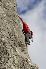 Image showing Young sports man climbing natural high rocky wall 