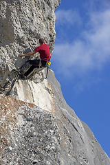 Image showing Young sports man climbing natural high rocky wall 