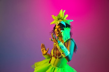 Image showing Beautiful young woman in carnival and masquerade costume on gradient studio background in neon light