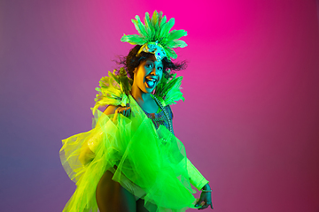 Image showing Beautiful young woman in carnival and masquerade costume on gradient studio background in neon light