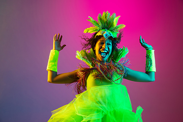 Image showing Beautiful young woman in carnival and masquerade costume on gradient studio background in neon light