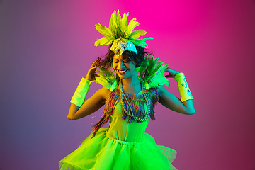 Image showing Beautiful young woman in carnival and masquerade costume on gradient studio background in neon light