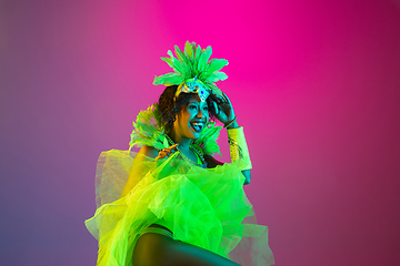 Image showing Beautiful young woman in carnival and masquerade costume on gradient studio background in neon light