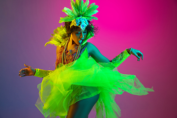 Image showing Beautiful young woman in carnival and masquerade costume on gradient studio background in neon light