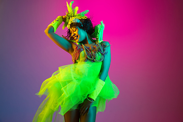 Image showing Beautiful young woman in carnival and masquerade costume on gradient studio background in neon light