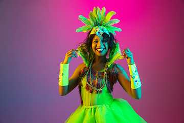 Image showing Beautiful young woman in carnival and masquerade costume on gradient studio background in neon light