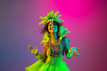 Image showing Beautiful young woman in carnival and masquerade costume on gradient studio background in neon light