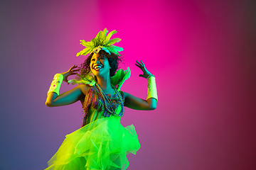 Image showing Beautiful young woman in carnival and masquerade costume on gradient studio background in neon light