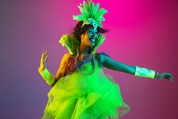 Image showing Beautiful young woman in carnival and masquerade costume on gradient studio background in neon light