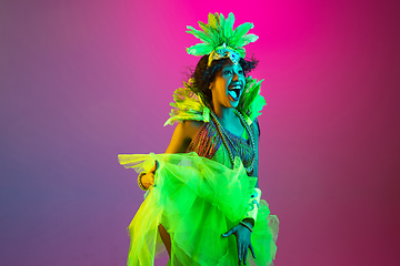 Image showing Beautiful young woman in carnival and masquerade costume on gradient studio background in neon light