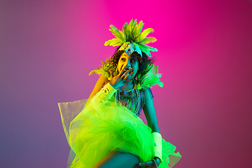 Image showing Beautiful young woman in carnival and masquerade costume on gradient studio background in neon light