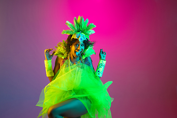 Image showing Beautiful young woman in carnival and masquerade costume on gradient studio background in neon light