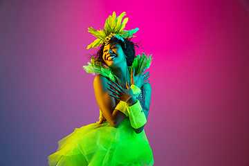 Image showing Beautiful young woman in carnival and masquerade costume on gradient studio background in neon light