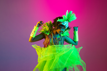 Image showing Beautiful young woman in carnival and masquerade costume on gradient studio background in neon light