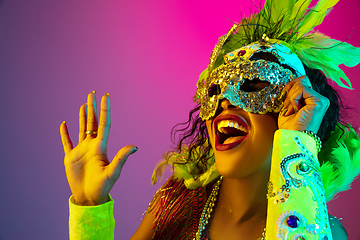 Image showing Beautiful young woman in carnival and masquerade costume on gradient studio background in neon light