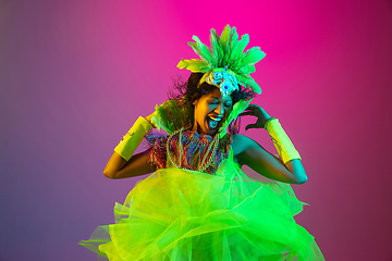 Image showing Beautiful young woman in carnival and masquerade costume on gradient studio background in neon light