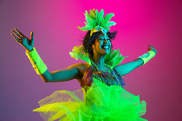 Image showing Beautiful young woman in carnival and masquerade costume on gradient studio background in neon light