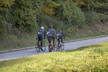 Image showing Group athletes cyclists riding a bike uphill along a road