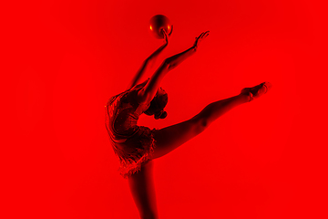 Image showing Young flexible female gymnast isolated on red studio background