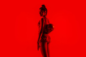 Image showing Young flexible female gymnast isolated on red studio background