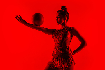 Image showing Young flexible female gymnast isolated on red studio background