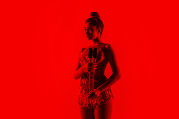 Image showing Young flexible female gymnast isolated on red studio background