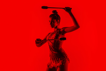 Image showing Young flexible female gymnast isolated on red studio background