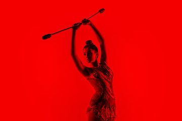 Image showing Young flexible female gymnast isolated on red studio background