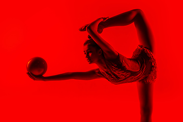 Image showing Young flexible female gymnast isolated on red studio background