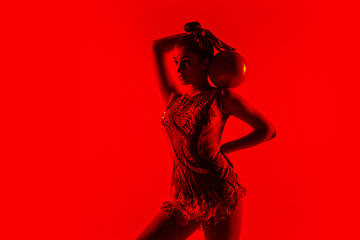 Image showing Young flexible female gymnast isolated on red studio background