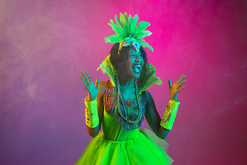 Image showing Beautiful young woman in carnival and masquerade costume on gradient studio background in neon light