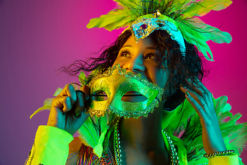 Image showing Beautiful young woman in carnival and masquerade costume on gradient studio background in neon light