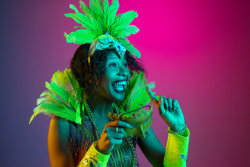 Image showing Beautiful young woman in carnival and masquerade costume on gradient studio background in neon light