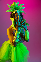 Image showing Beautiful young woman in carnival and masquerade costume on gradient studio background in neon light