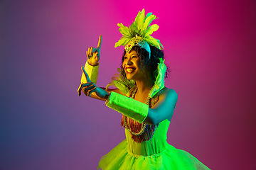 Image showing Beautiful young woman in carnival and masquerade costume on gradient studio background in neon light