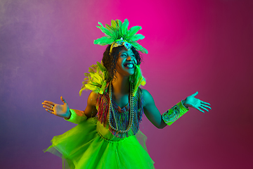 Image showing Beautiful young woman in carnival and masquerade costume on gradient studio background in neon light