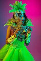 Image showing Beautiful young woman in carnival and masquerade costume on gradient studio background in neon light