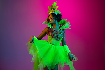 Image showing Beautiful young woman in carnival and masquerade costume on gradient studio background in neon light