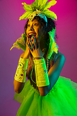 Image showing Beautiful young woman in carnival and masquerade costume on gradient studio background in neon light