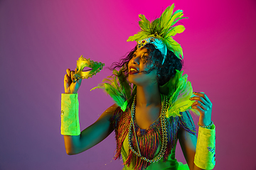 Image showing Beautiful young woman in carnival and masquerade costume on gradient studio background in neon light