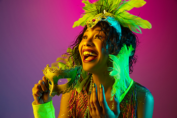 Image showing Beautiful young woman in carnival and masquerade costume on gradient studio background in neon light