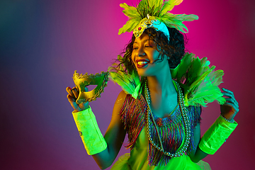 Image showing Beautiful young woman in carnival and masquerade costume on gradient studio background in neon light