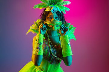 Image showing Beautiful young woman in carnival and masquerade costume on gradient studio background in neon light