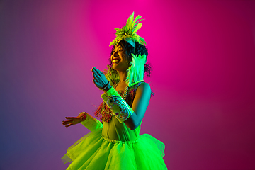 Image showing Beautiful young woman in carnival and masquerade costume on gradient studio background in neon light