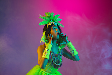 Image showing Beautiful young woman in carnival and masquerade costume on gradient studio background in neon light