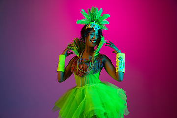 Image showing Beautiful young woman in carnival and masquerade costume on gradient studio background in neon light