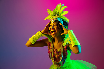 Image showing Beautiful young woman in carnival and masquerade costume on gradient studio background in neon light