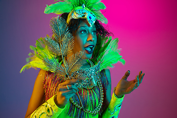 Image showing Beautiful young woman in carnival and masquerade costume on gradient studio background in neon light